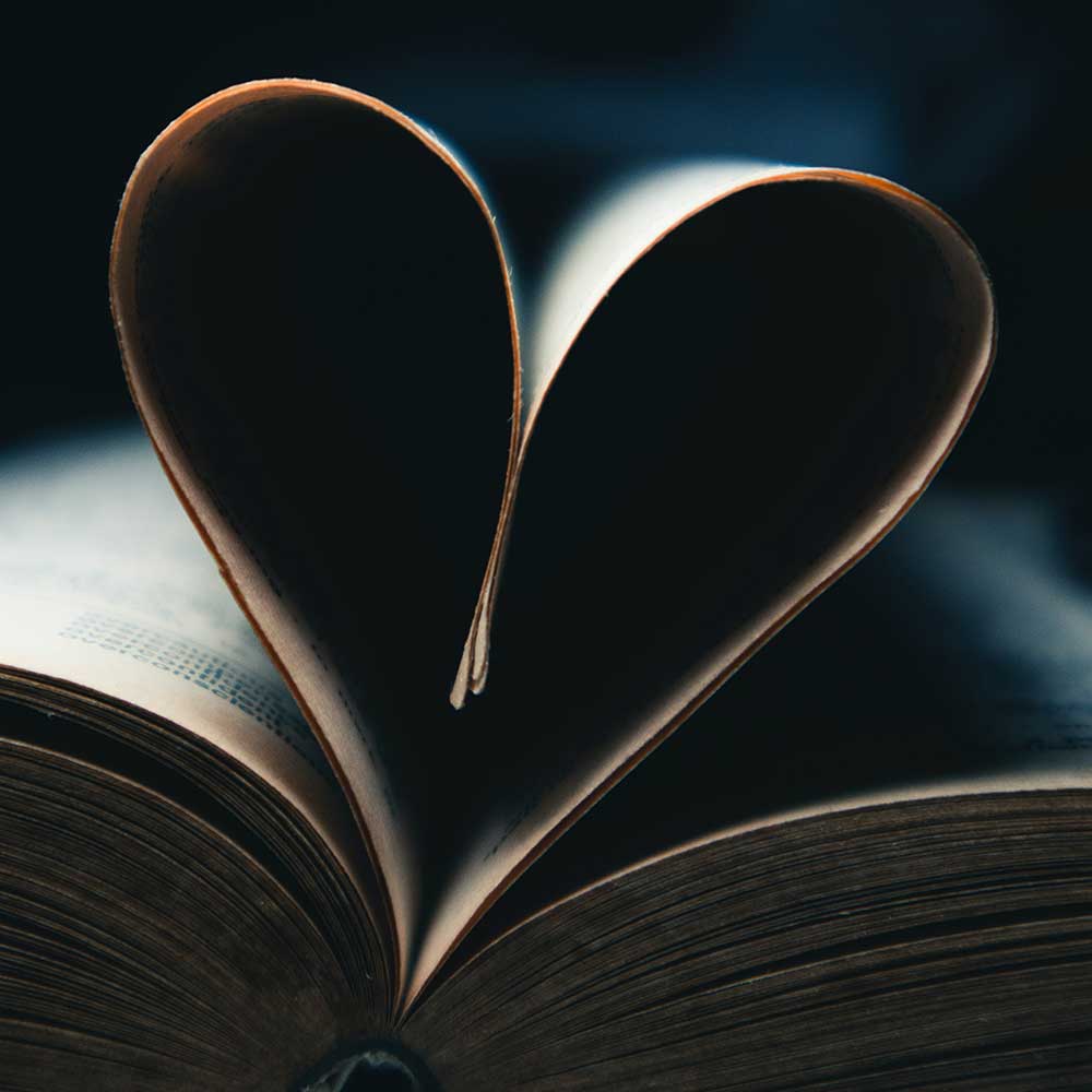 an open book with a heart shaped bookmark